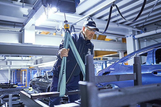 A Leadec employee troubleshooting the conveyor system in an automotive factory.