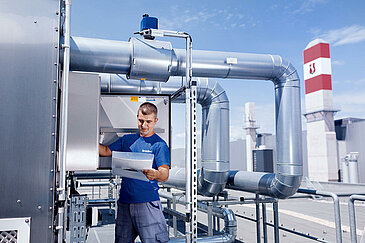 Leadec employee on roof checks external installation of ventilation system.